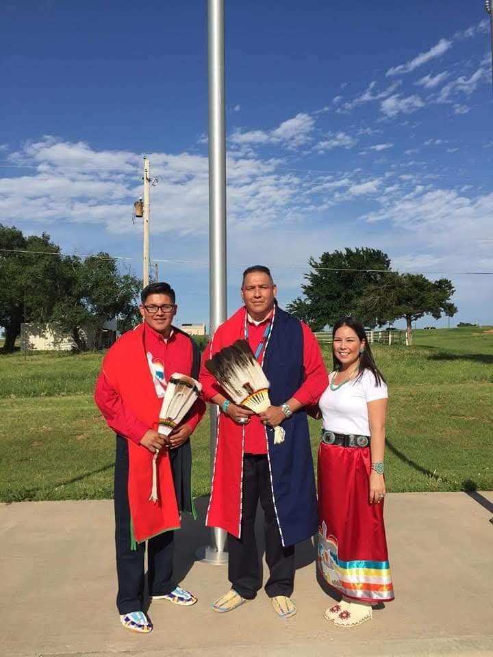 Community members wearing traditional clothing gathered outdoors